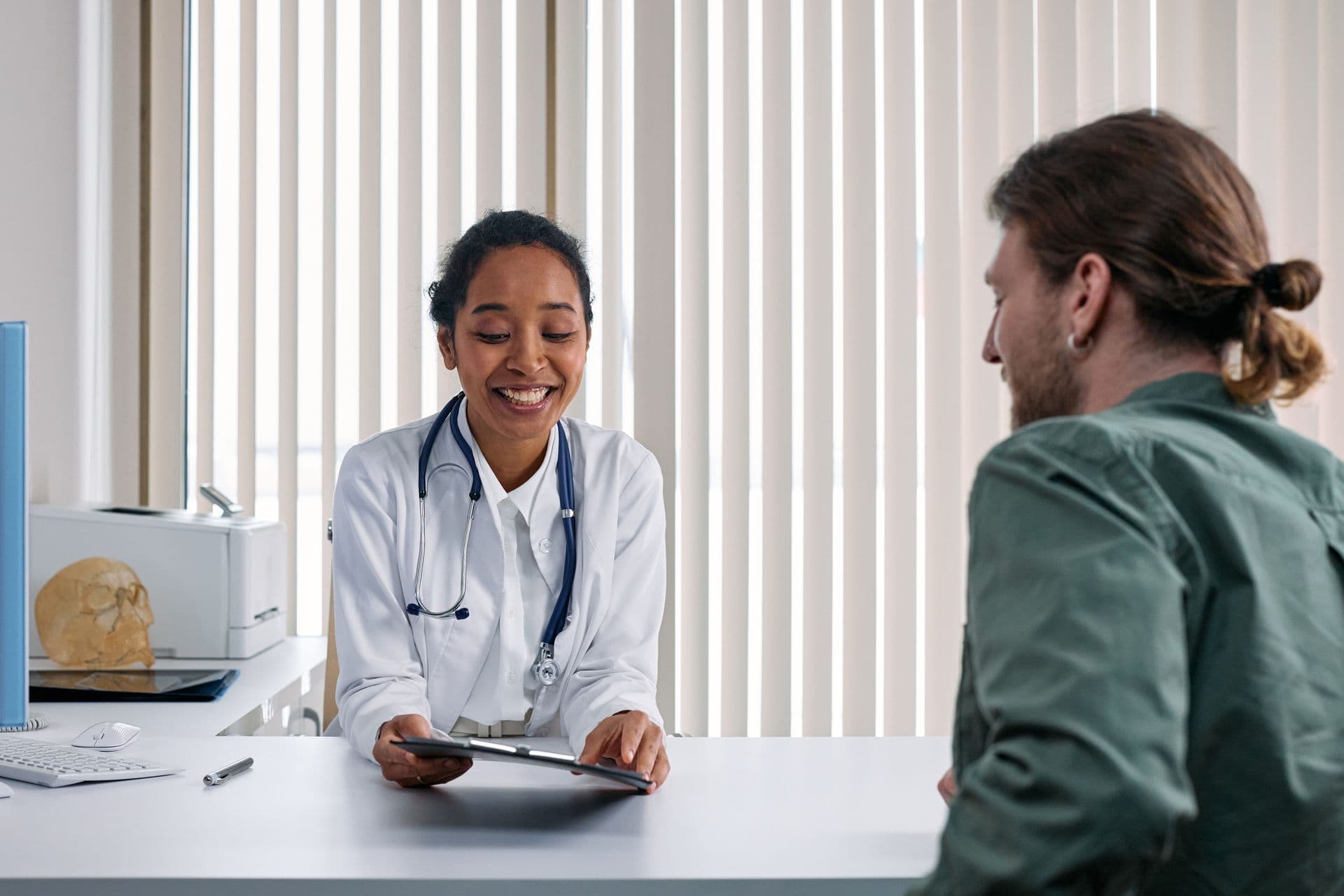A GP talking through notes with a patient in a consulting room