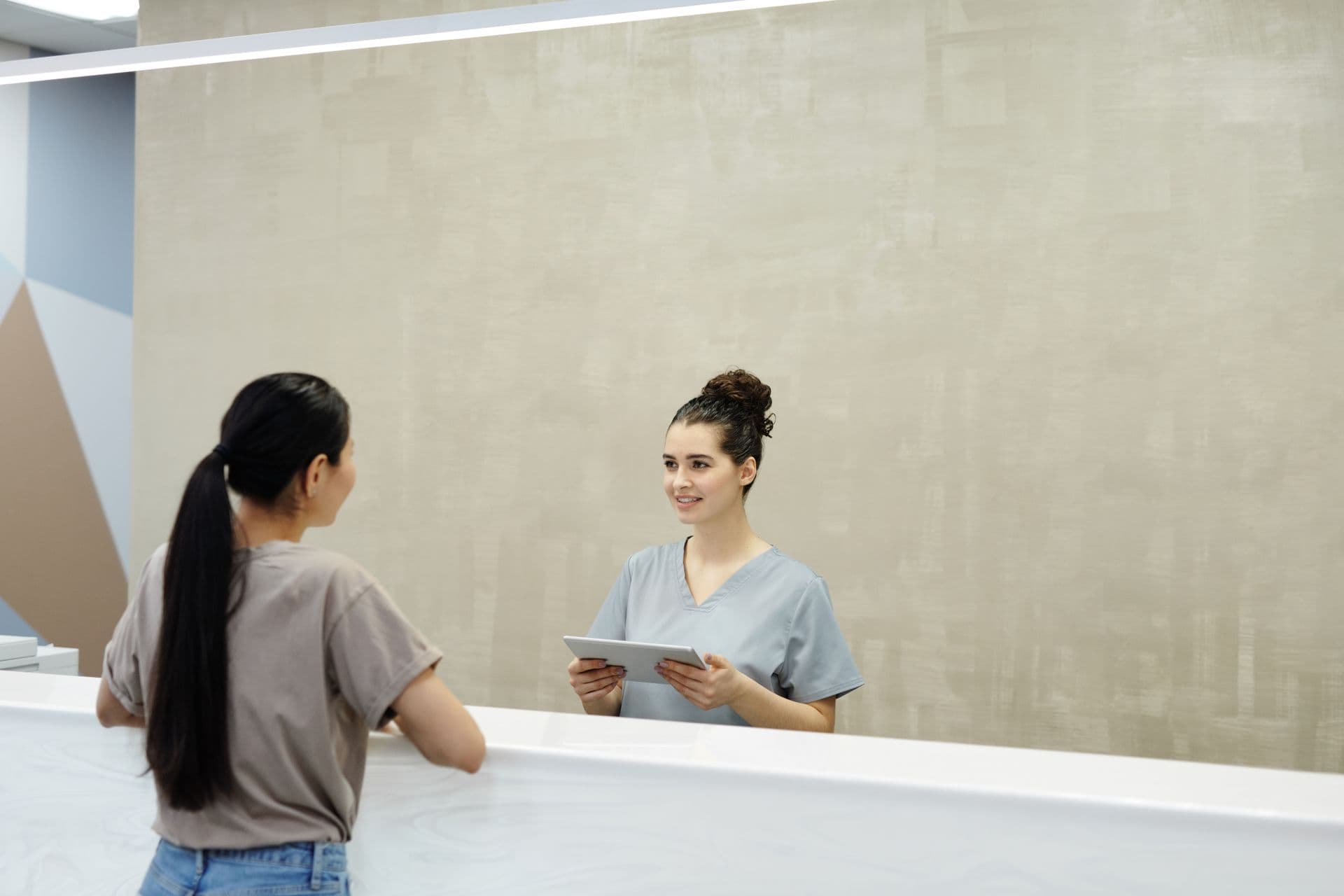 A receptionist welcoming a patient at the surgery front desk
